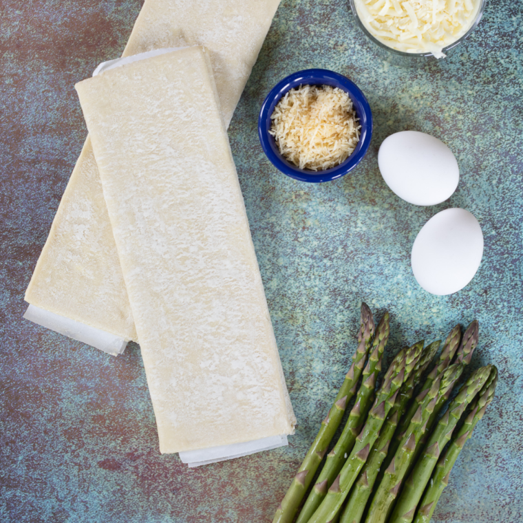 Ingredients needed for Air Fryer Asparagus Puff Pastry Bundles on kitchen table.