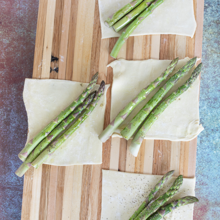 Roll out puff pastry into a rectangle, cut into six pieces, drizzle asparagus with olive oil, and season with salt and pepper.