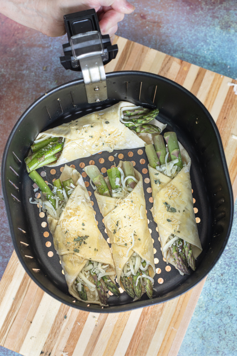 Arrange the asparagus puff pastry bundles in the air fryer and cook until golden brown.