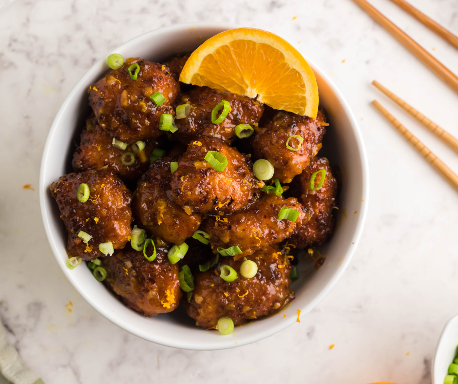 Air Fryer Orange Chicken (Panda Express Copycat) served on a plate with a side of rice and garnished with sesame seeds and green onions"