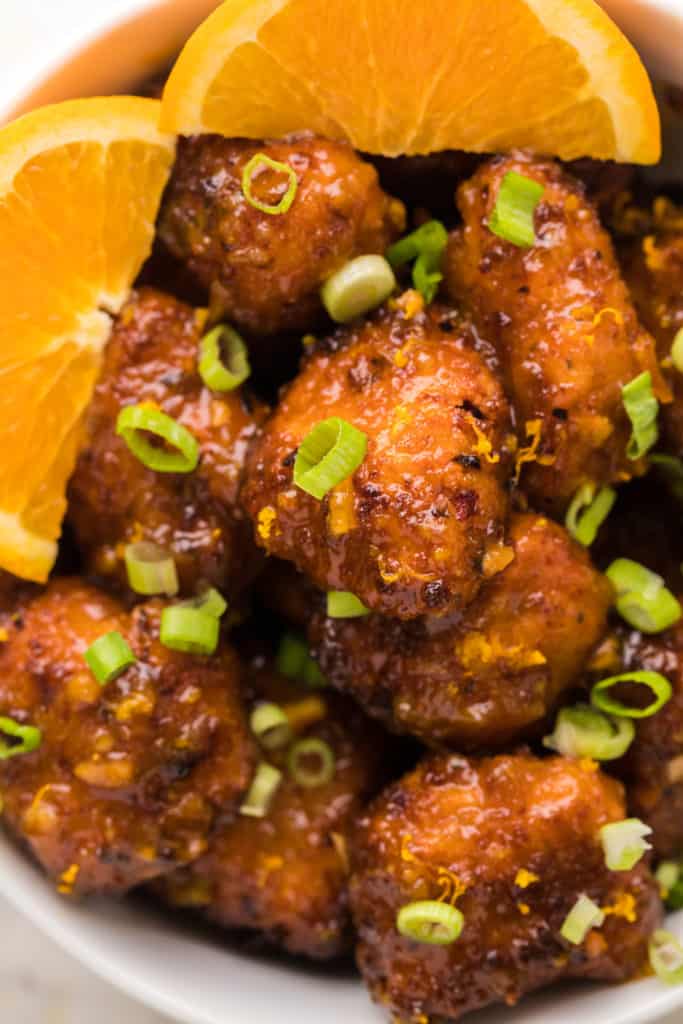 "Finished Air Fryer Orange Chicken drizzled with sauce and garnished with green onions"