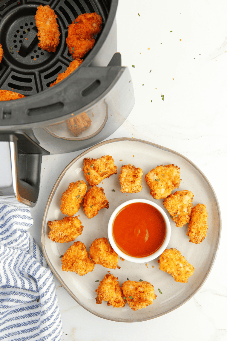 Hand holding a crispy popcorn chicken piece showing crunchy breading texture