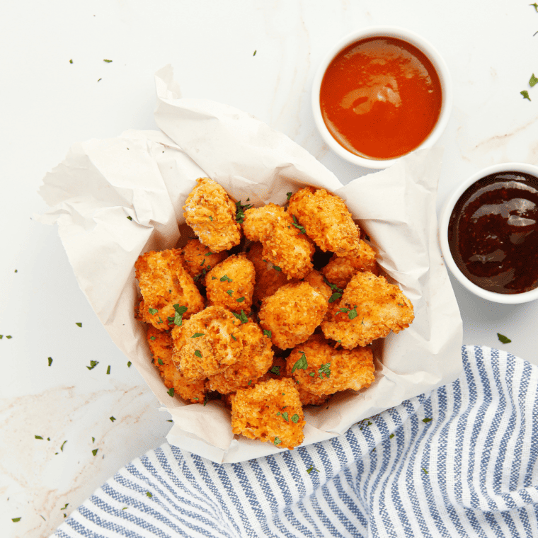 Air fryer basket filled with crispy popcorn chicken bites fresh out of cooking