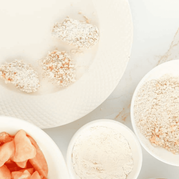 Step-by-step breading process for air fryer popcorn chicken showing marinated chicken being coated in flour, dipped in egg, and pressed into seasoned panko before air frying