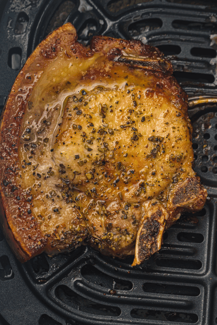 Sliced air fryer ranch pork chop showing a juicy interior beside vegetable sides