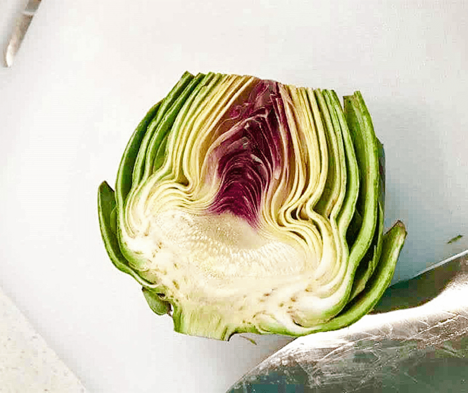 Hand plucking the small outer leaves from the base of a fresh artichoke