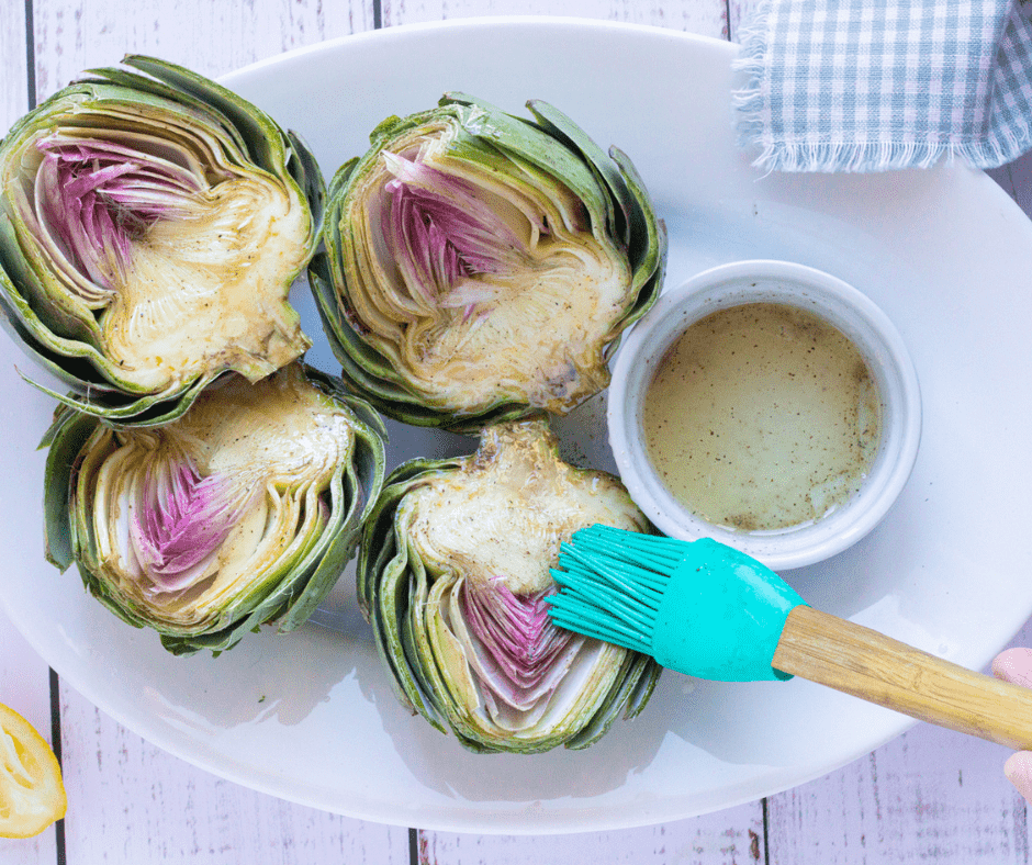 Knife trimming the top third off an artichoke before air frying.