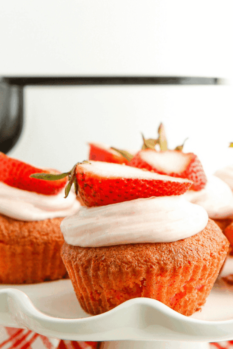 Two strawberry cupcakes with swirled pink frosting on a white plate.