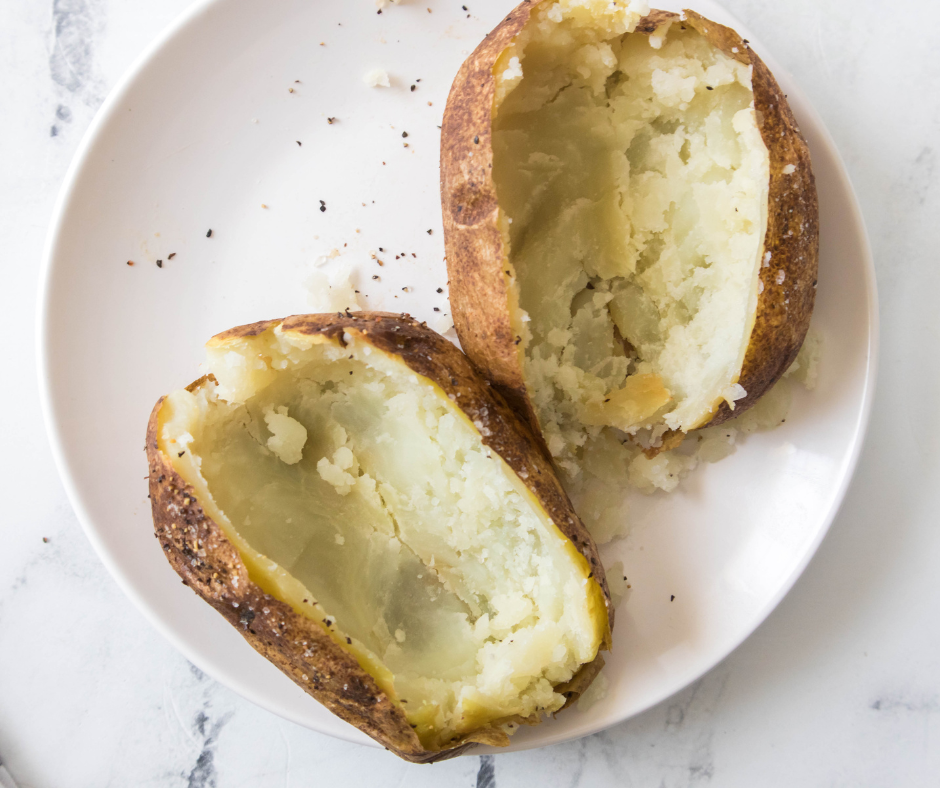 Baked potatoes on a white plate with insides scooped out.