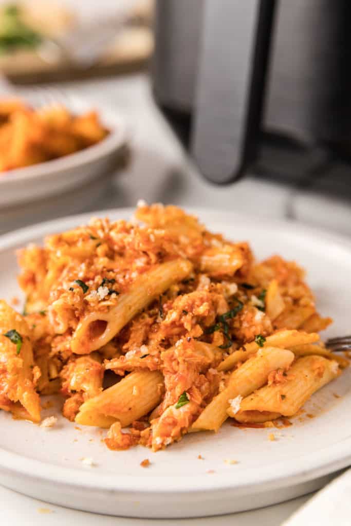  A delicious Air Fryer Chicken Parmesan Casserole topped with melted cheese and fresh basil, served in a dish with a golden-brown crust, showcasing a hearty portion ready to be enjoyed.