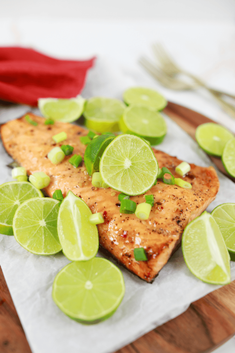 Cedar plank salmon cooked on a wooden plank, flaky and glazed, served with lemon and fresh herbs.