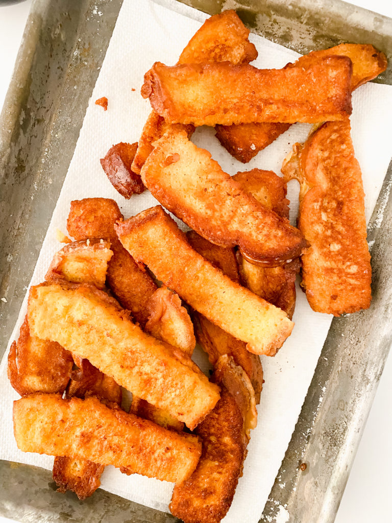 Golden brown air fryer French toast sticks served with syrup.