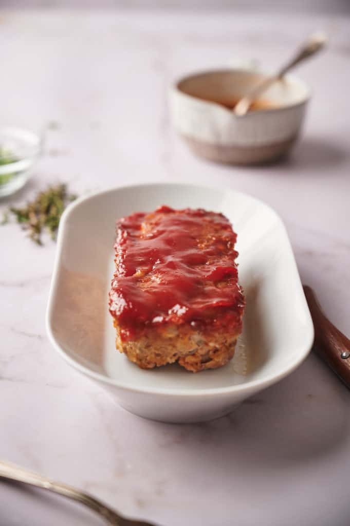 Air Fryer Meatloaf glazed with bourbon sauce served on a plate with sides.