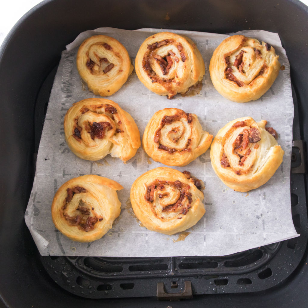Flaky air fryer breakfast pinwheels filled with bacon, cheddar cheese, and brown sugar, served golden and crisp on a plate