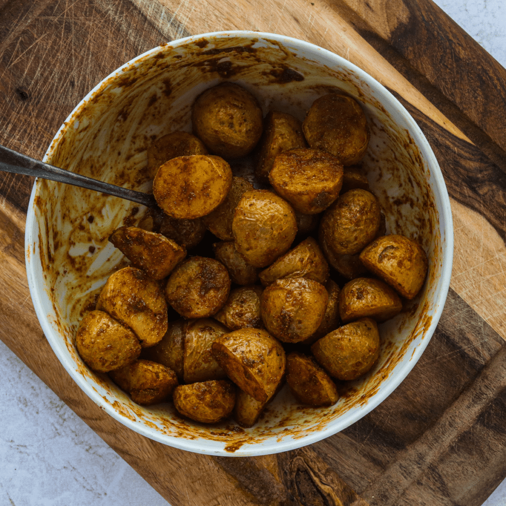 Returning seasoned potatoes to the air fryer basket, cooking at 400°F for 5-7 minutes until crispy and golden brown