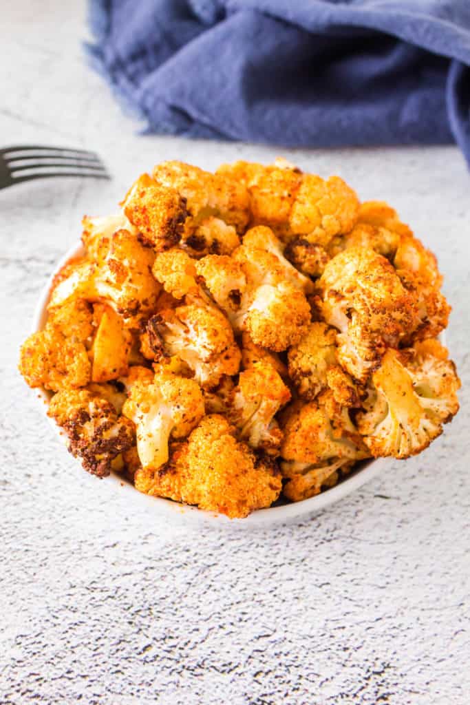  Plate of Tandoori Cauliflower featuring golden-brown, crispy pieces of cauliflower marinated in a spiced yogurt mixture, garnished with fresh herbs and served with a side of dipping sauce