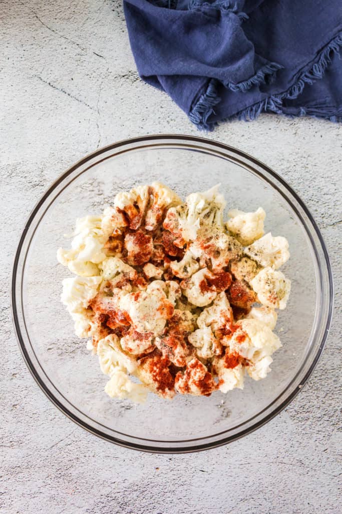 Image of cauliflower florets being mixed with a spiced yogurt marinade.
