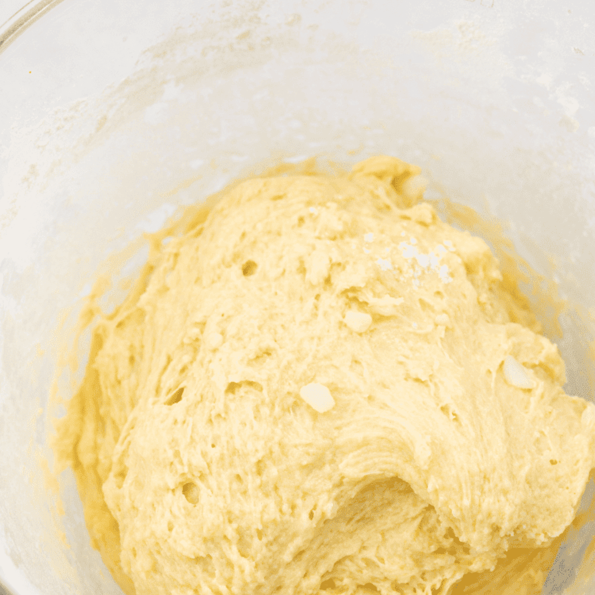 Adding yeast mixture to dough, forming dough balls, and placing in greased dish for rising.