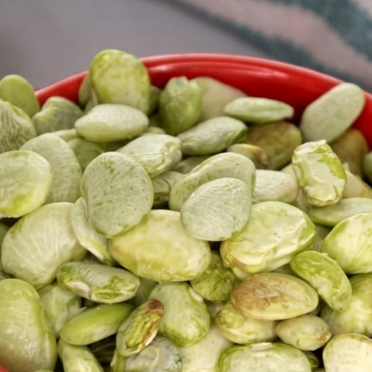 Frozen lima beans roasting inside an air fryer basket during cooking