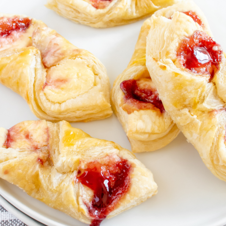 Air fryer puff pastry Danish stacked on a plate beside a mug of coffee