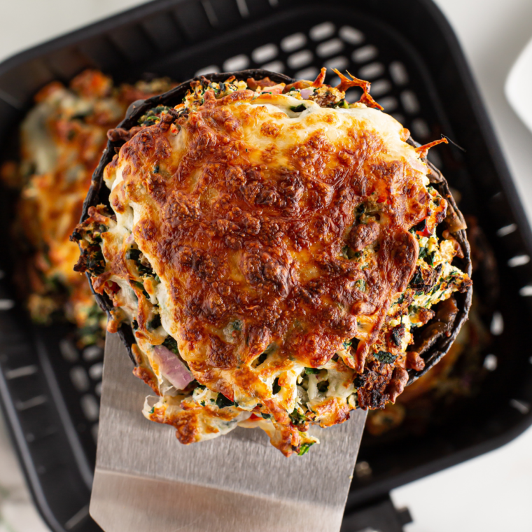 Air fryer stuffed portobello mushrooms filled with ricotta, spinach, bacon, and topped with mozzarella cheese, cooked to perfection.