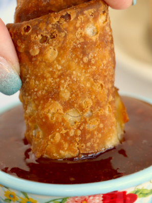 Crispy air fried Chung's egg roll being dipped into sweet and sour sauce