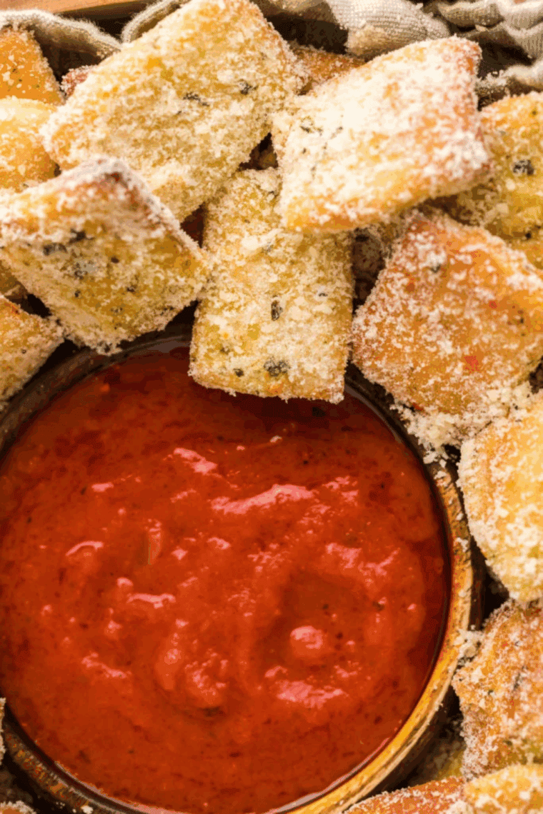 A pile of small, golden-brown homemade Domino's style garlic bread knots, heavily brushed with melted butter and topped with Parmesan cheese and dried herbs.