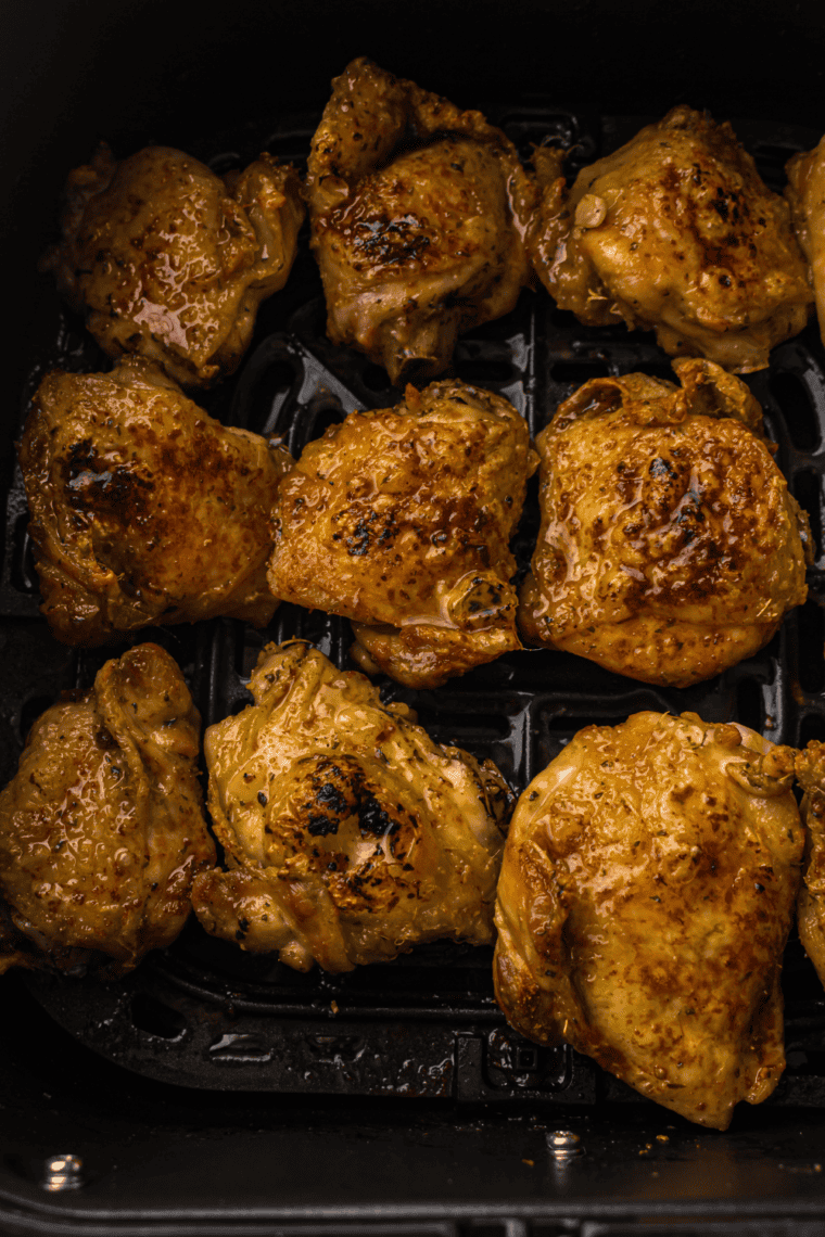 Cooked chicken thighs resting on a plate for juices to redistribute.