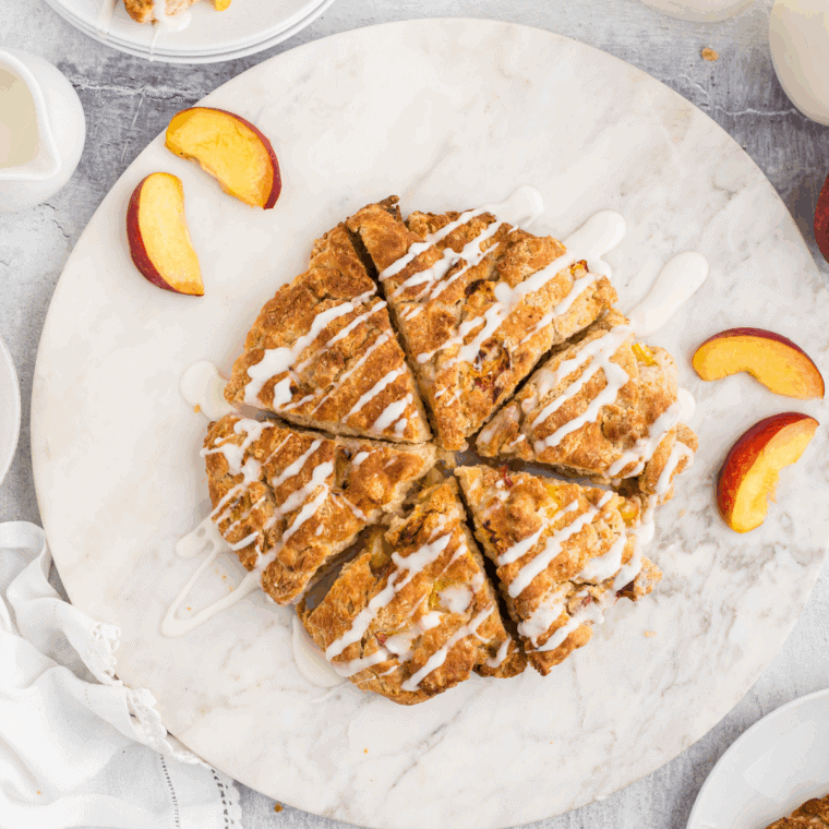 Peach scones drizzled with cream glaze on a serving plate