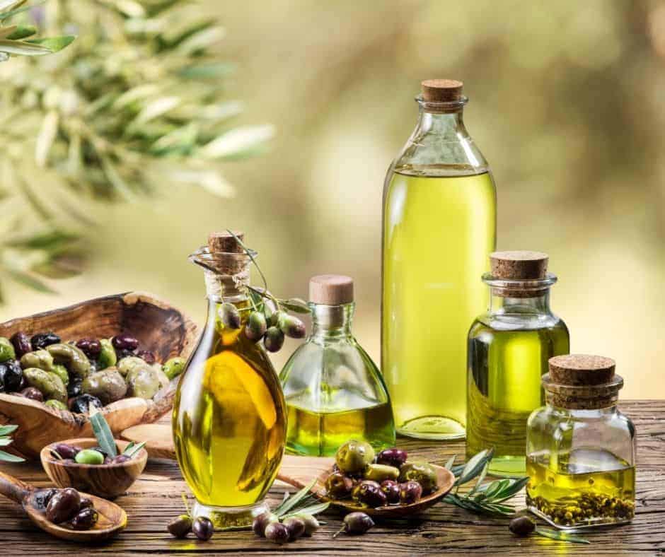 An assortment of oil in air fryer options on a wooden table with bowls of olives.