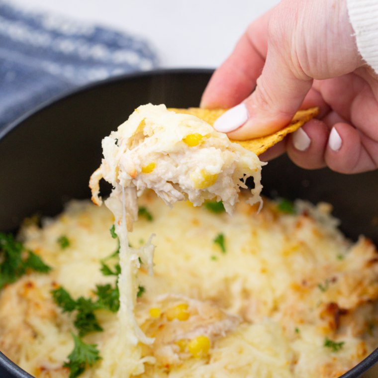 Cheesy air fryer white chicken chili dip in a skillet, golden and bubbling, surrounded by tortilla chips