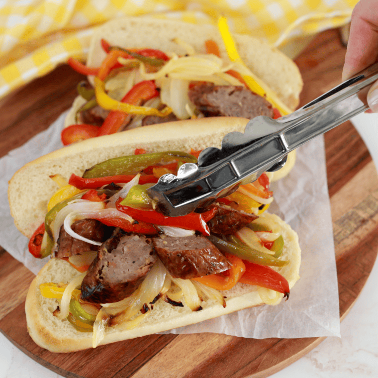 Air fryer brat topped with grilled peppers and onions in a hoagie roll
