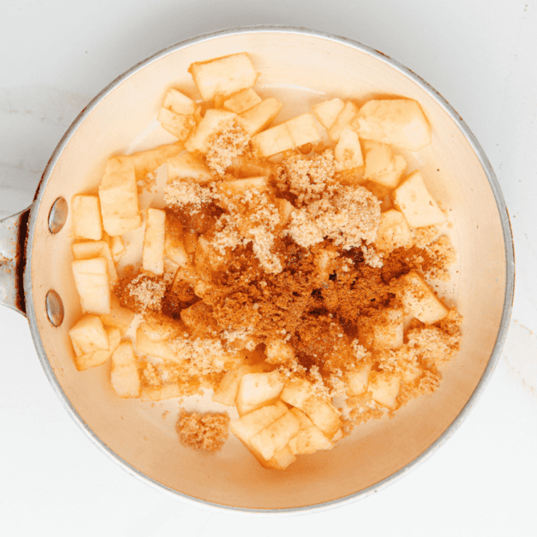 Diced apples cooking in a small saucepan with cinnamon and nutmeg until softened.