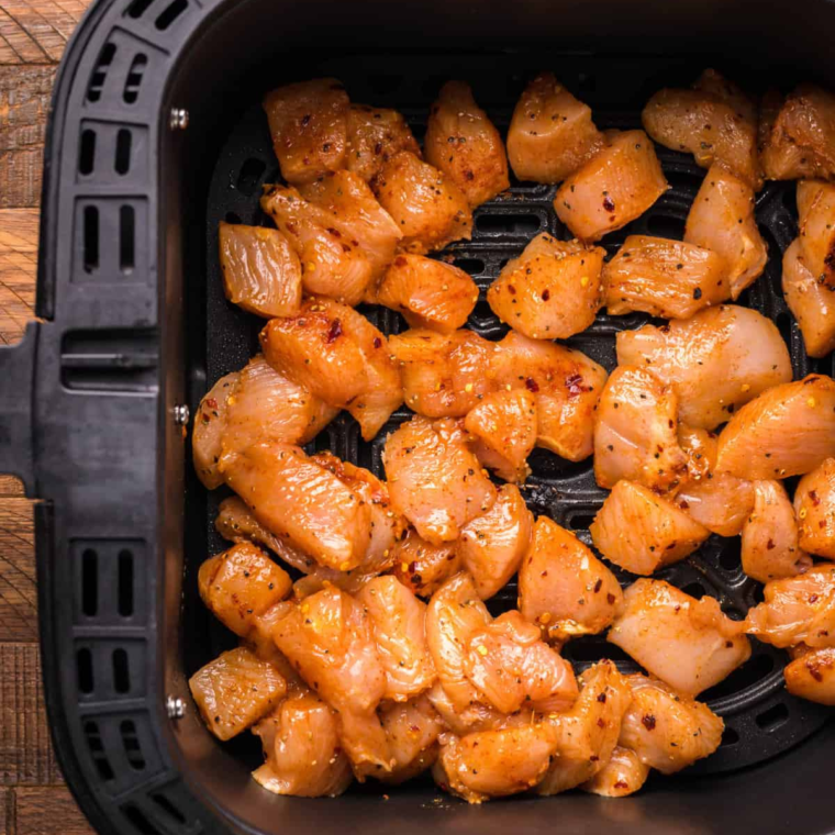 Chicken pieces being tossed in seasoned flour before air frying.