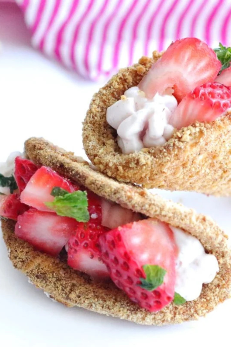 Strawberry cheesecake tacos topped with fresh diced strawberries in crispy graham-coated shells