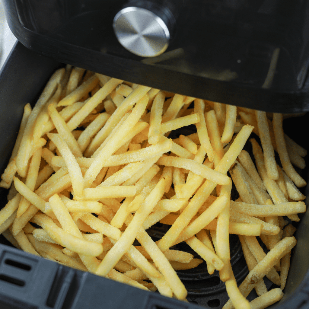 Placing frozen French fries in a single layer in the air fryer basket, ready for cooking.