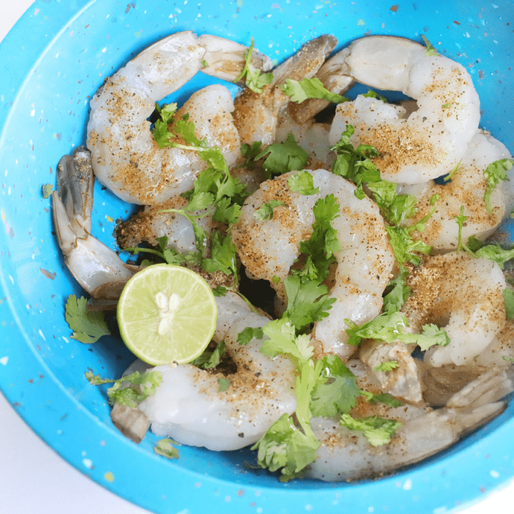 Sliced bell peppers and onions tossed with oil and spices in an air fryer basket at 370°F.