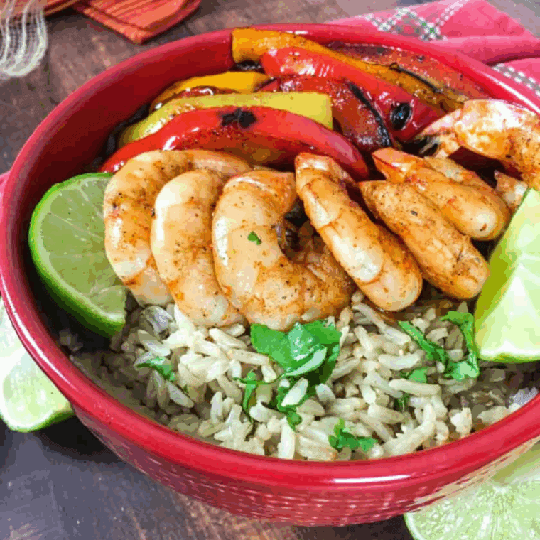 Air fryer shrimp fajita bowl with juicy shrimp, charred peppers and onions, rice, lime, and cilantro.