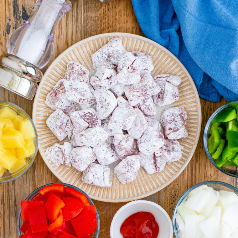 Raw pork shoulder cut into one-inch cubes on a cutting board