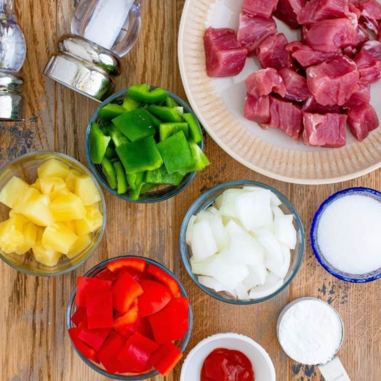 Ingredients for air fryer sweet and sour pork including cubed pork, pineapple, bell peppers, and sauce