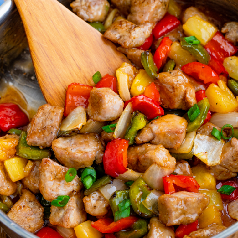 Sweet and sour pork with chopsticks lifting a piece of crispy pork