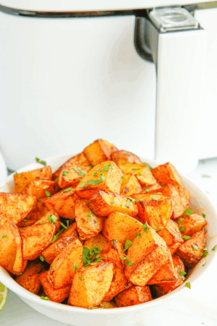 Air fryer chili lime potatoes, golden and crispy on the outside, tender inside, garnished with lime wedges and spices.