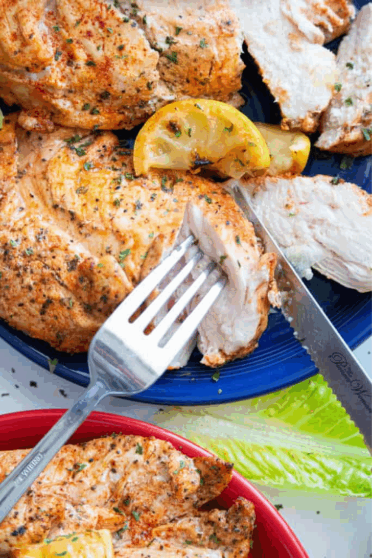 Golden-brown Ninja Foodi lemon chicken with fresh lemon slices and herbs
