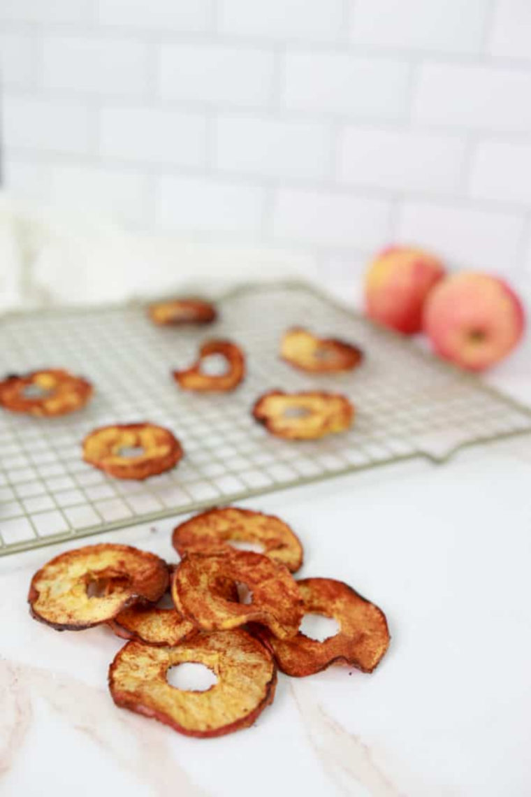 Golden brown dehydrated apple slices arranged in an air fryer tray after cooking.