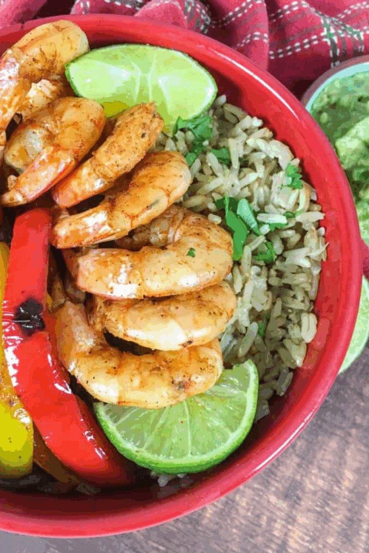 Close-up of a colorful shrimp fajita bowl with avocado, lime, and fresh herbs.