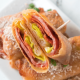 Air fryer antipasto egg rolls on a white platter with a bowl of Italian dressing
