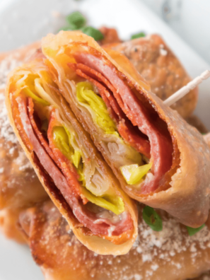 Air fryer antipasto egg rolls on a white platter with a bowl of Italian dressing