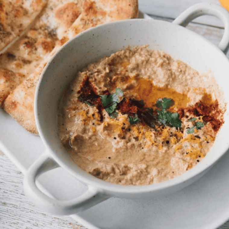 Air fryer baba ganoush in a bowl drizzled with olive oil, served with pita and fresh veggies
