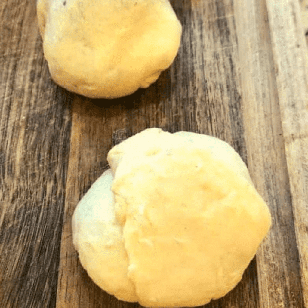 Filling dough with blueberry pie filling and sealing into round pie bombs.