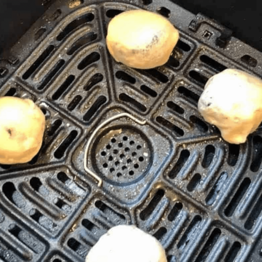 Air fryer basket with blueberry pie bombs spaced evenly, ready to cook until golden brown.